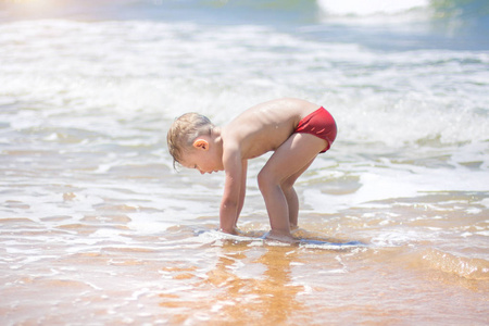 小男孩在海里游泳, 在纯净的波浪中奔跑和飞溅