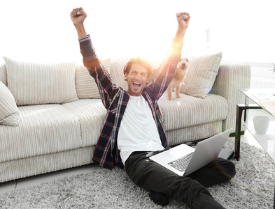 快乐的年轻人狂喜与他的狗坐在客厅里照片