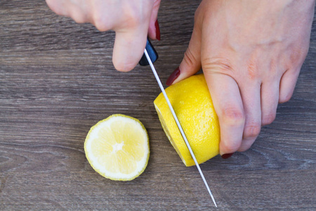女性手把柠檬切成块在木板上