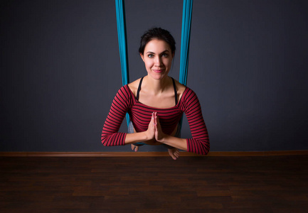 年轻漂亮的女人做飞瑜伽.坐在吊床上双手合十的手势.