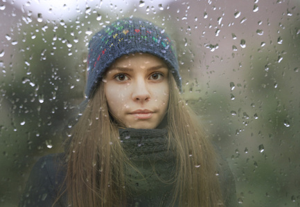 年轻女孩看窗外雨滴