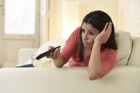 年轻漂亮的女人在家里看电视累和无聊照片