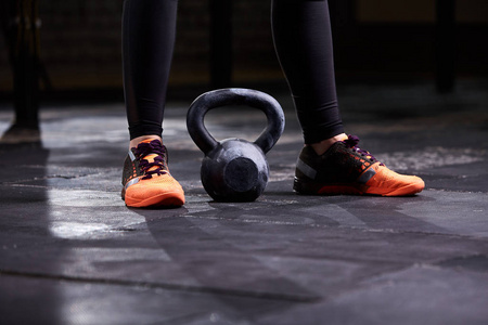 年轻女人，腿中的黑色紧身裤和橙色运动鞋，壶的裁剪的图像。运动量来找到锻炼