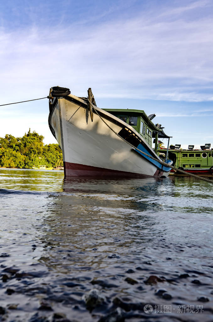 渔夫的船停泊在阴天和蓝色天空背景在阳光灿烂的日子