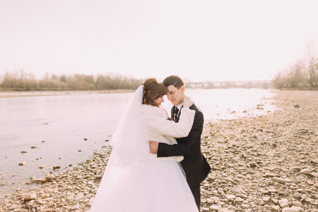 幸福的新婚夫妇，新娘和新郎拥抱面对面整洁河