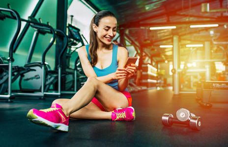 年轻运动妇女使用智能手机在健身房