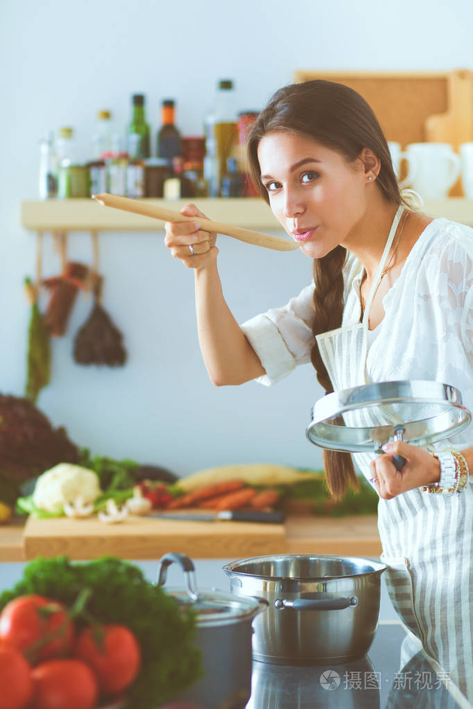 厨房里用木勺做饭的女人.烹调妇女