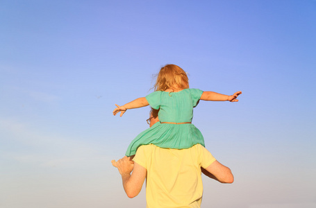 父亲和肩膀上的小女儿玩着天空