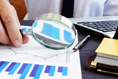 审计员与放大镜检查财务报告照片
