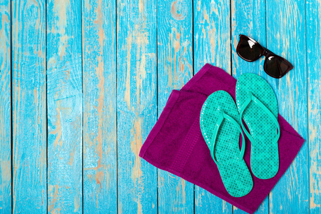 彩色木质背景的毛巾和太阳镜拖鞋, 顶部视图