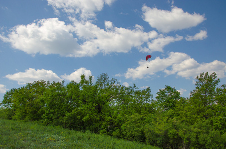 剪影的操控滑翔伞飞行在天空中的云彩日出的光芒。乌克兰喀尔巴阡谷