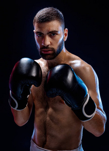 在黑色拳击手套强壮的肌肉拳击手。拳击中的在黑色的背景上