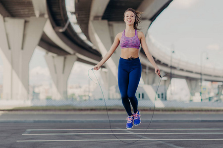 活泼的女人与欢快的表情做有氧训练与跳绳, 穿着运动服, 有运动的生活方式, 健康的身体。运动女性训练刻苦。健康的生活方式概念