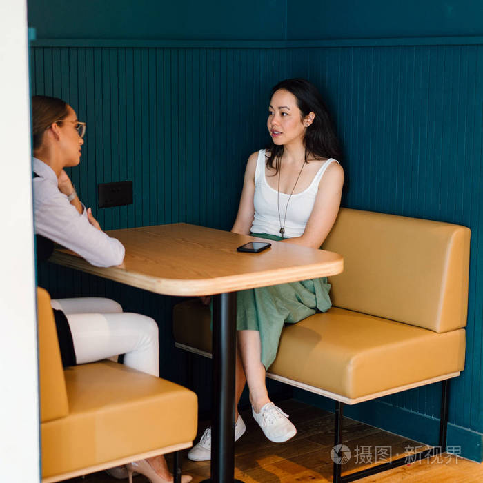 两位女商人坐在桌子的现代办公室全长