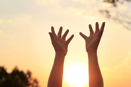 女人双手祈求上帝上日落背景的祝福