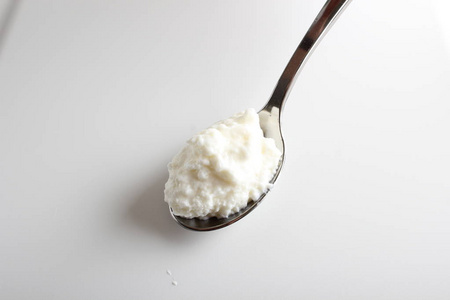 小屋奶酪酸奶在一个白色的背景勺子