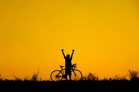 在美丽的日落背景下, 骑自行车的朋友在运动的剪影