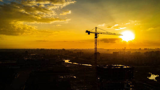 夜太阳背景下建筑起重机的剪影