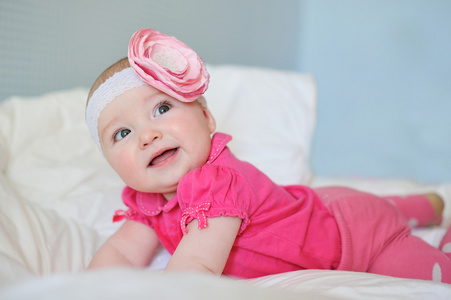 胖胖的脸颊，穿着粉色的衣服和带花惊讶可爱的小宝宝