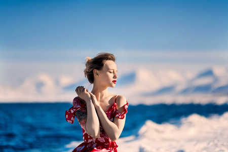 女孩穿着红色山脉斯瓦尔巴群岛在斯匹次卑尔根市朗伊尔城，在阳光明媚的天气背景霜苗条美丽的金发女郎