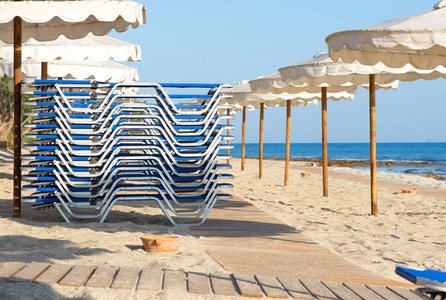日光浴折叠和雨伞在海滩上