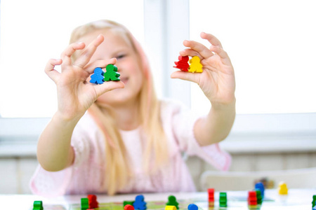 棋盘游戏和儿童休闲概念小金发女孩有乐趣, 笑和沉迷玩棋盘游戏。掌握人物的手。黄色, 蓝色, 绿色木片