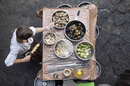 夏季烧烤食品的照片。一个男人在串上串菜的看法