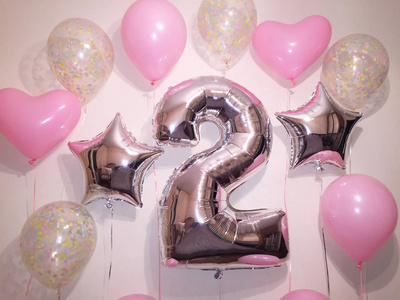 氦气球组成的粉红色, 透明的五彩纸屑, 粉红色的心, 银色的星星和一个大的两个数字。给一个小女孩的生日礼物