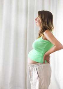 怀孕，孕产特写的幸福怀孕的女人在室内