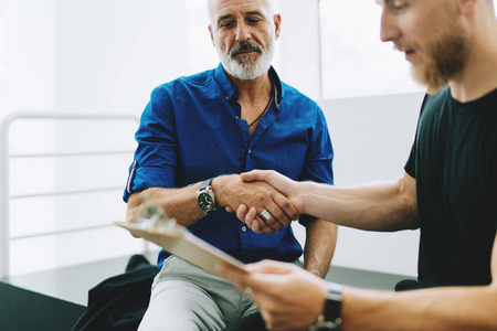 年轻的企业家在休闲服装与投资者握手照片