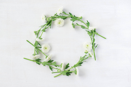 白色木质的白色花朵美妙的花环。圆的菊花框架。花卉图案的最高视图。美丽的春天构图。平躺的花朵