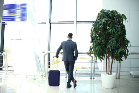 商务男人带在机场大厅里的手提箱