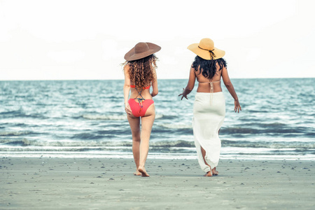 快乐的比基尼妇女在夏季的热带沙滩上一起日光浴。旅游生活方式