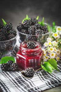 成熟的黑莓和黑莓果酱在木桌上。深色背景