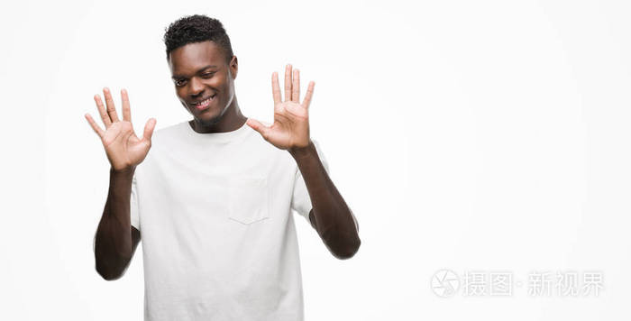 年轻的非洲裔美国人穿着白色 t恤显示和指向十的手指, 而微笑着自信和快乐