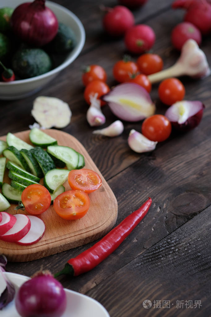 新鲜蔬菜切片的沙拉在一个旧的木桌上切板上