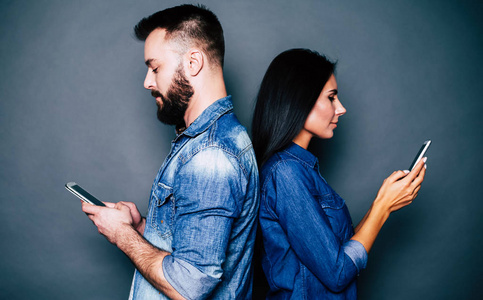 年轻夫妇使用智能手机灰色背景