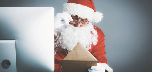 圣诞老人阅读儿童的信件和书面答复他们使用笔记本电脑