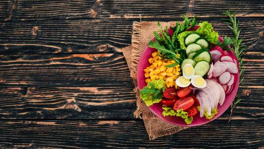 新鲜蔬菜沙拉。玉米, 萝卜, 洋葱, 黄瓜, 鹌鹑蛋。在一个木质的背景。顶部视图。自由复制空间