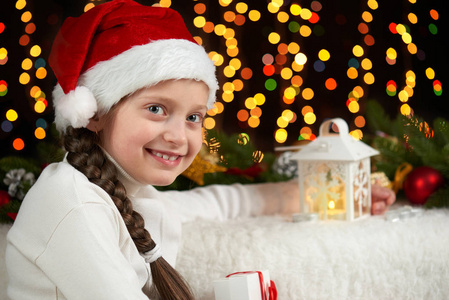 儿童女孩肖像与圣诞装饰，黑暗的背景灯 面部表情和快乐的情绪，穿着圣诞老人的帽子，冬天假日概念