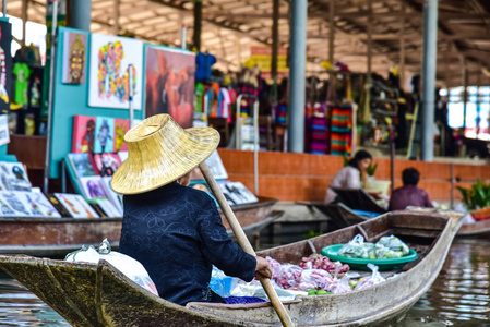 泰国女子与一艘船在曼谷附近的水上市场合作