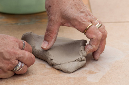 老妇人的手特写在室外制作粘土陶碗