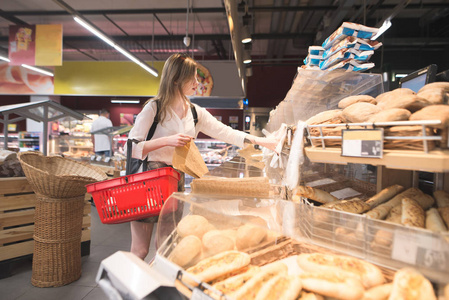 篮子里买在超市面包部门买面包的女孩的肖像.