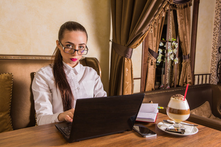 在咖啡馆里用笔记本电脑工作的年轻女子