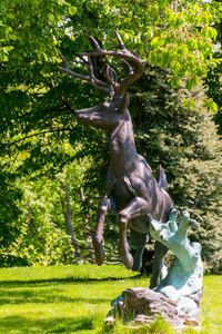 一只小鹿的一个有趣的雕像, 树枝状的角准备跳跃站在树荫下的公园里