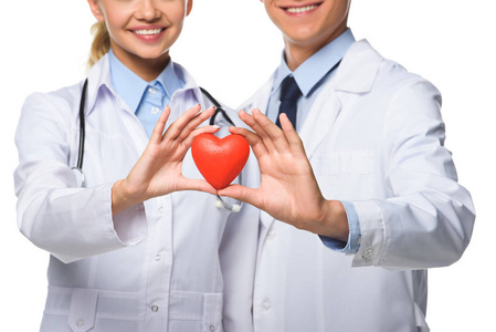 两位医生在白色大衣持有红色心脏, 隔离白色的看法