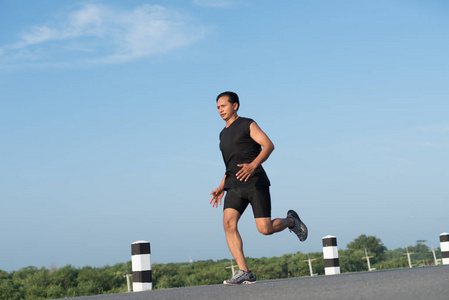 亚洲年轻人奔跑在时间在日出期间在水坝路锻炼。健康的生活方式