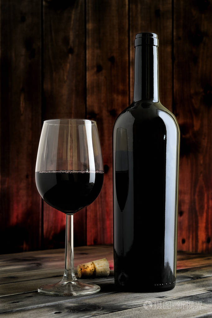 特写镜头的红酒杯和一张古色古香的木桌上的瓶子