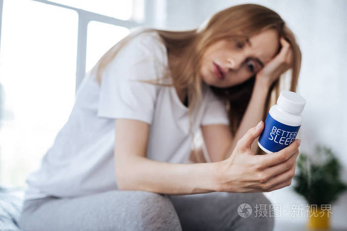 全神贯注的女人看着她的安眠药照片-正版商用图片0qrxp4-摄图新视界