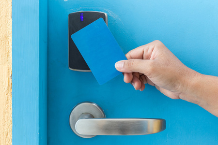 钥匙卡手拿着蓝色酒店钥匙卡在电动门照片
